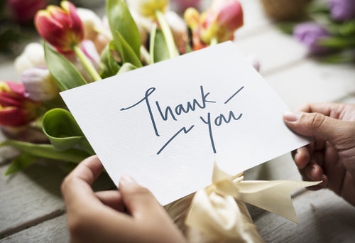 hands holding thank you card with flowers in background