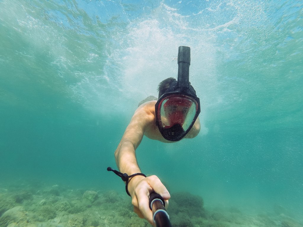 man using selfie stick underwater