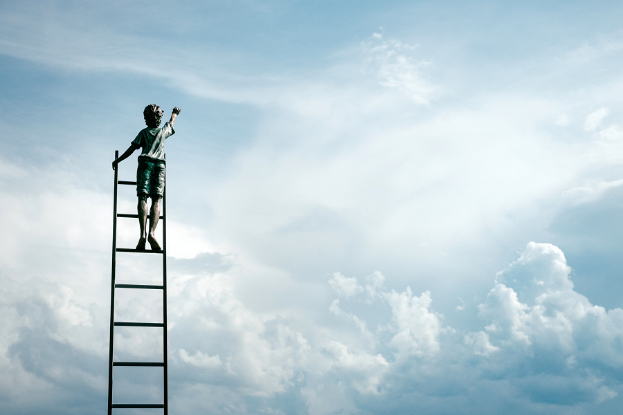 boy on ladder reaching for clouds