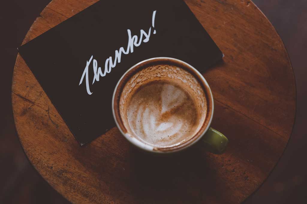 Coffee cup on a table next to a note that says, “Thanks!” for Administrative Professional Day