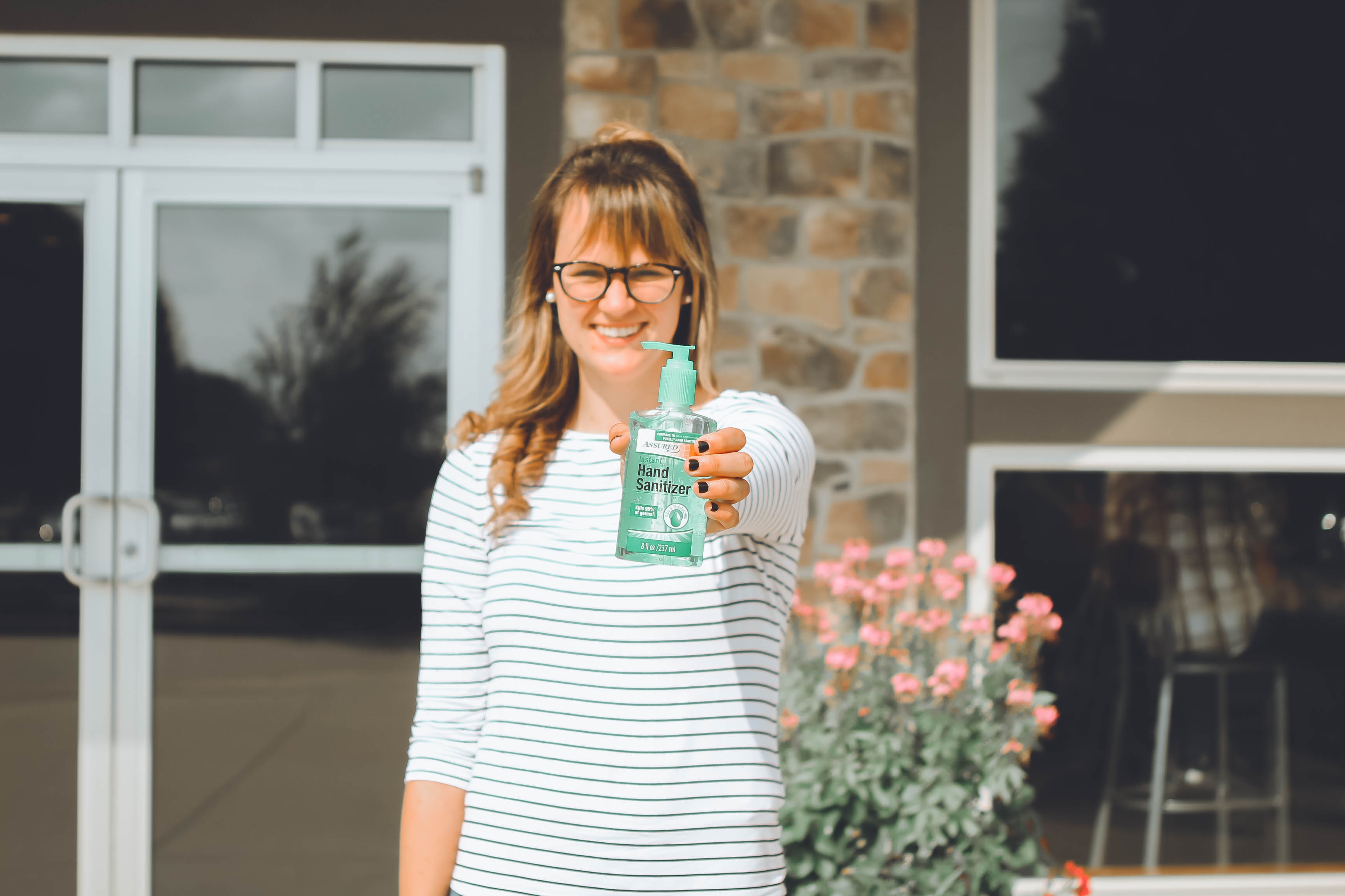 Smiling woman holding hand sanitizer in front of home