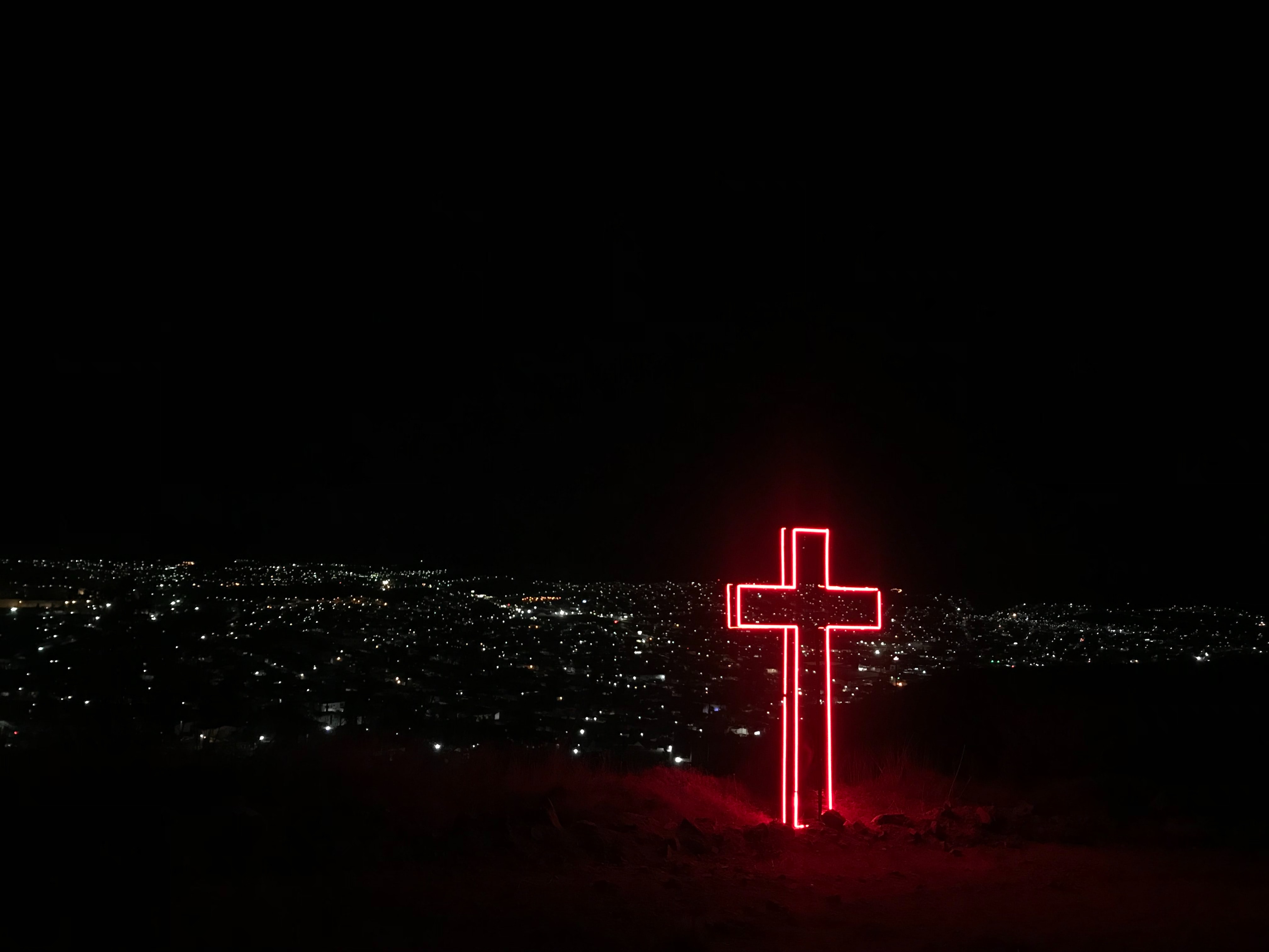 neon cross at night with view