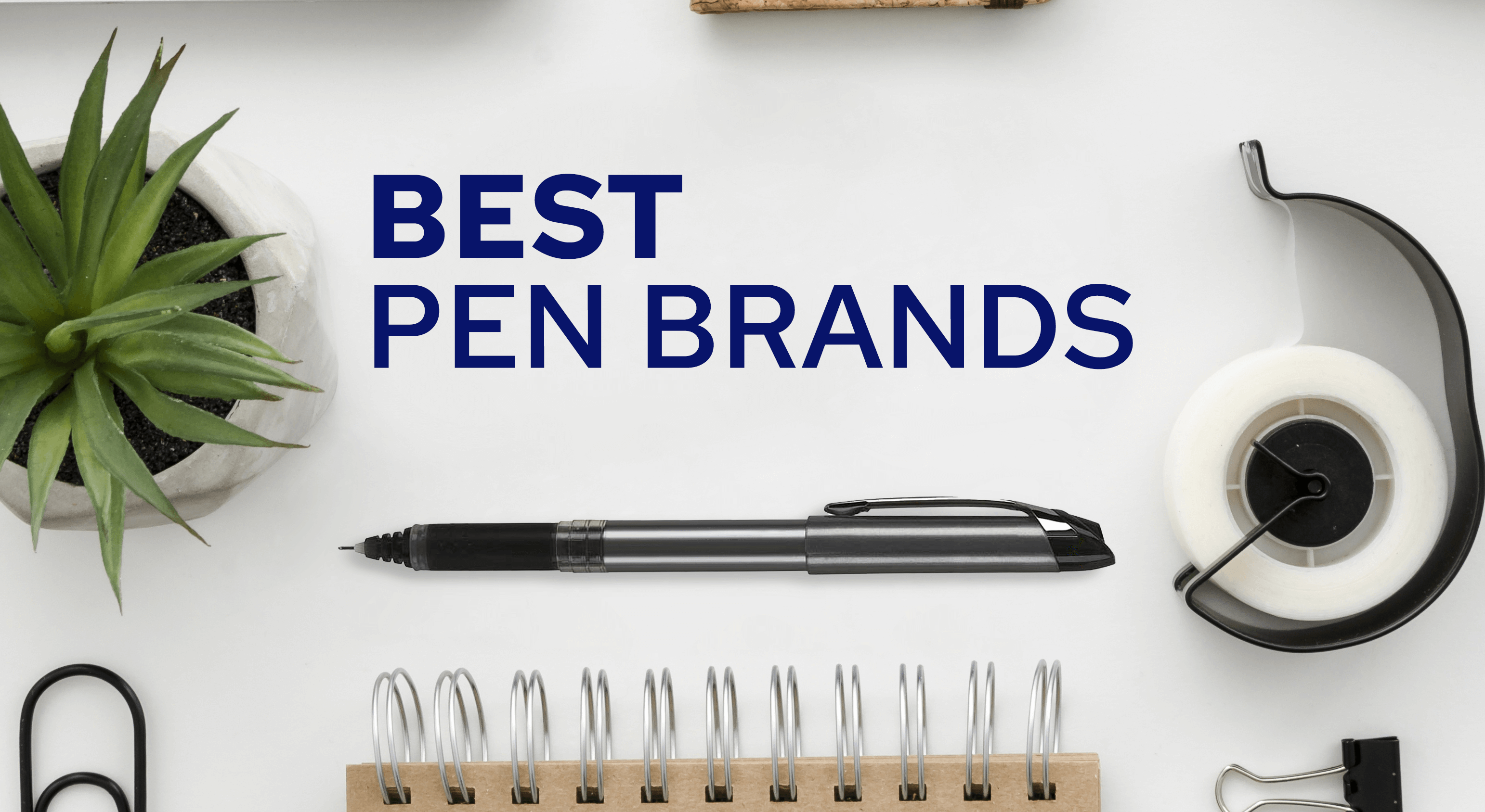 Best pen brand on desk with other accessories including plant, notebook, clip, and tape.