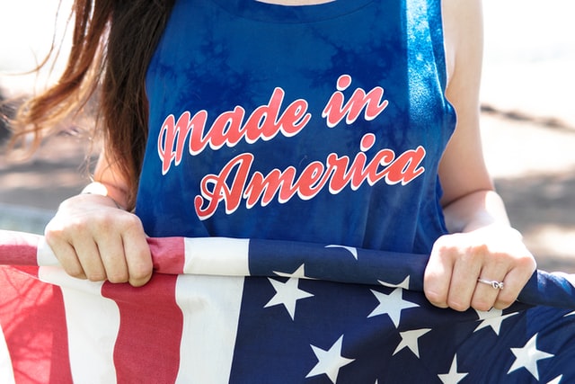 Person holding USA flag and wearing "Made in America" t-shirt
