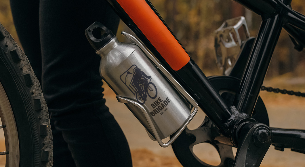 Metal water bottle in bike bottle cage on bike with rider