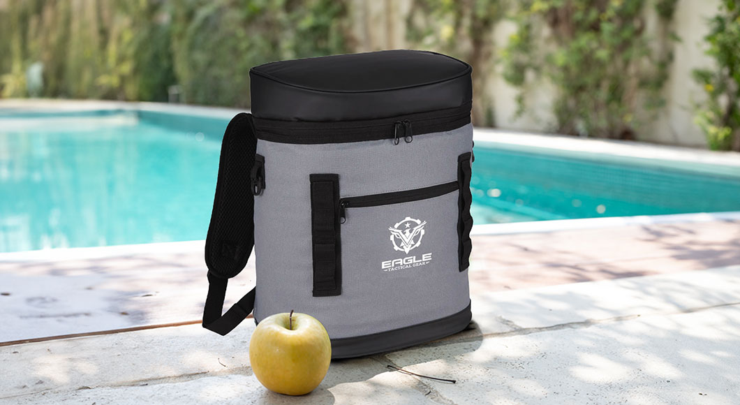 Grey cooler backpack by pool in summertime with an apple