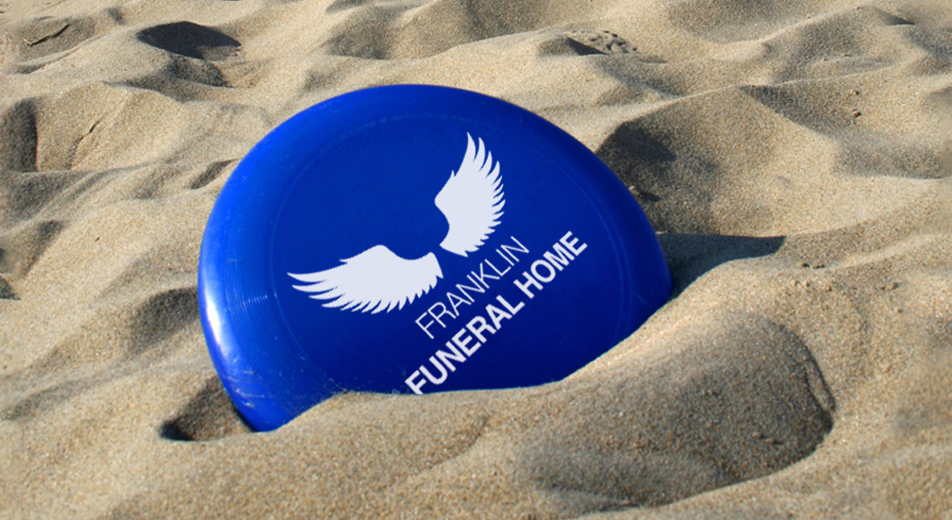 frisbee in sand with customized logo for funeral home in support of promotional product fails blog