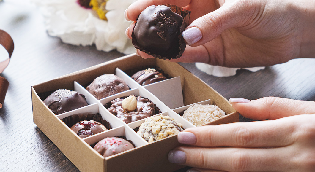 Person's hand choosing gourmet chocolate from gift box