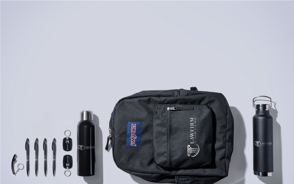 Legal promotional items banner displaying dark colored metal pens, bottle opener, water bottles keychains and Jansport backpack imprinted with a lawfirm logo.