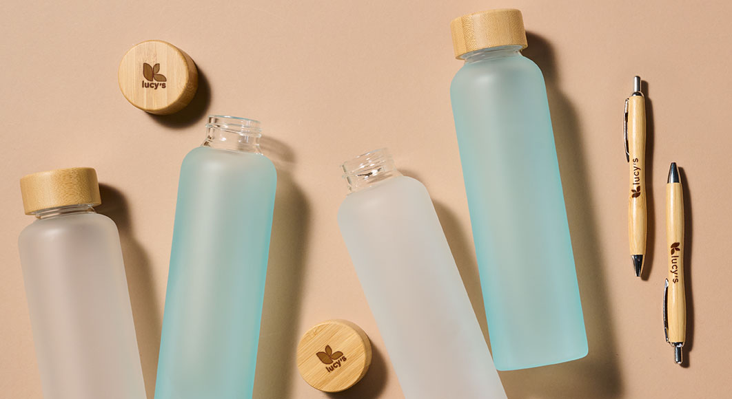Personalisierte Kugelschreiber aus Bambus mit Lasergravur und Trinkflasche aus Mattglas mit individuellem Bambusdeckel mit Lasergravur.