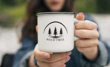 Persona che tiene tra le mani una tazza bianca con logo